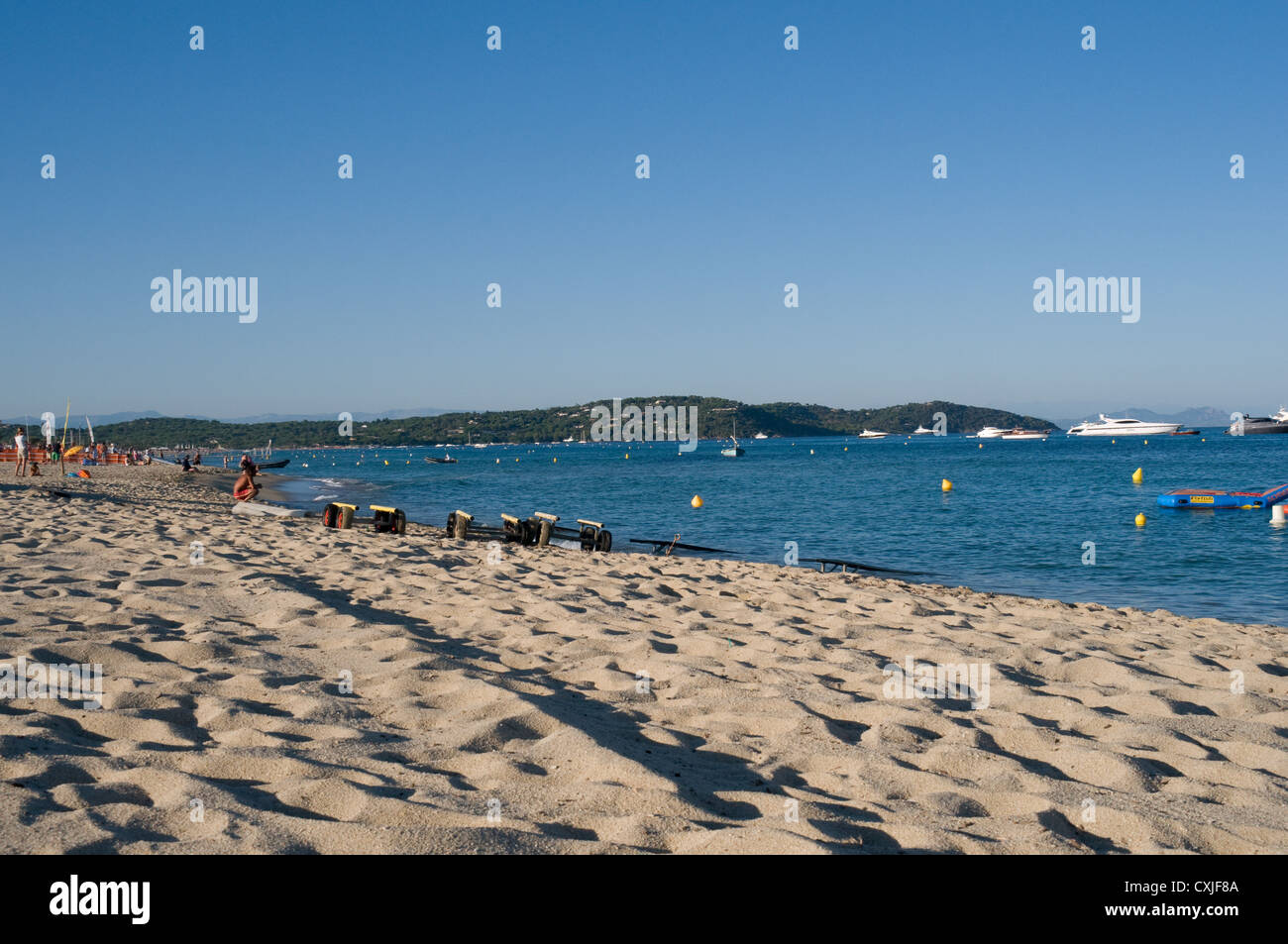 Il turista a godere la sabbiosa spiaggia di Pampelonne nel sud della Francia vicino a St Tropez. barche di lusso sono ormeggiate nella baia. Foto Stock