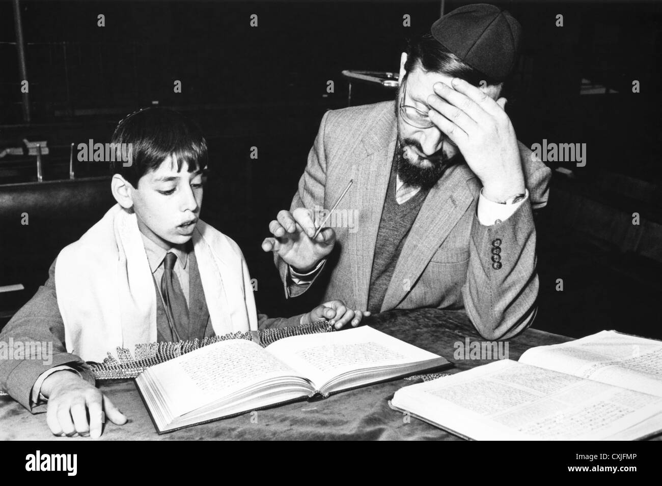 Giovane ragazzo ebreo di ricevere istruzioni per bar mitzvà dal rabbino nella sinagoga degli anni ottanta Cardiff South Wales UK Foto Stock