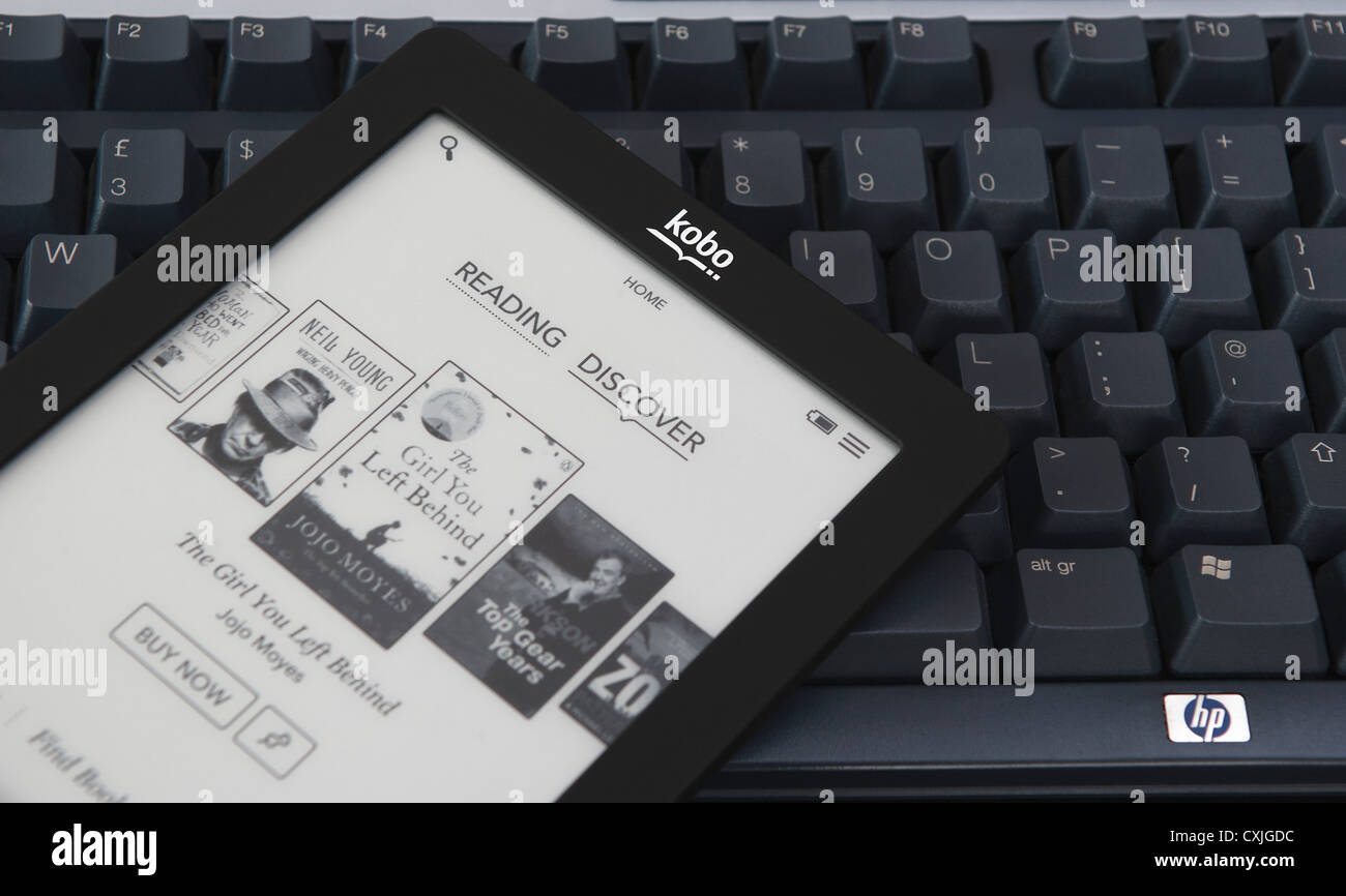 Un Kobo touch ereader (ebook) è mostrato fotografato seduto sulla parte superiore della tastiera di un computer. Foto Stock