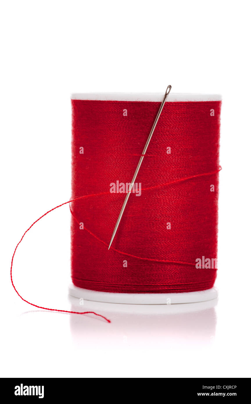 Bobina di filo rosso e un ago su sfondo bianco Foto Stock