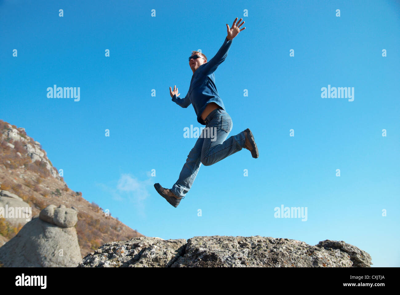 L'uomo saltando sulle rocce Foto Stock