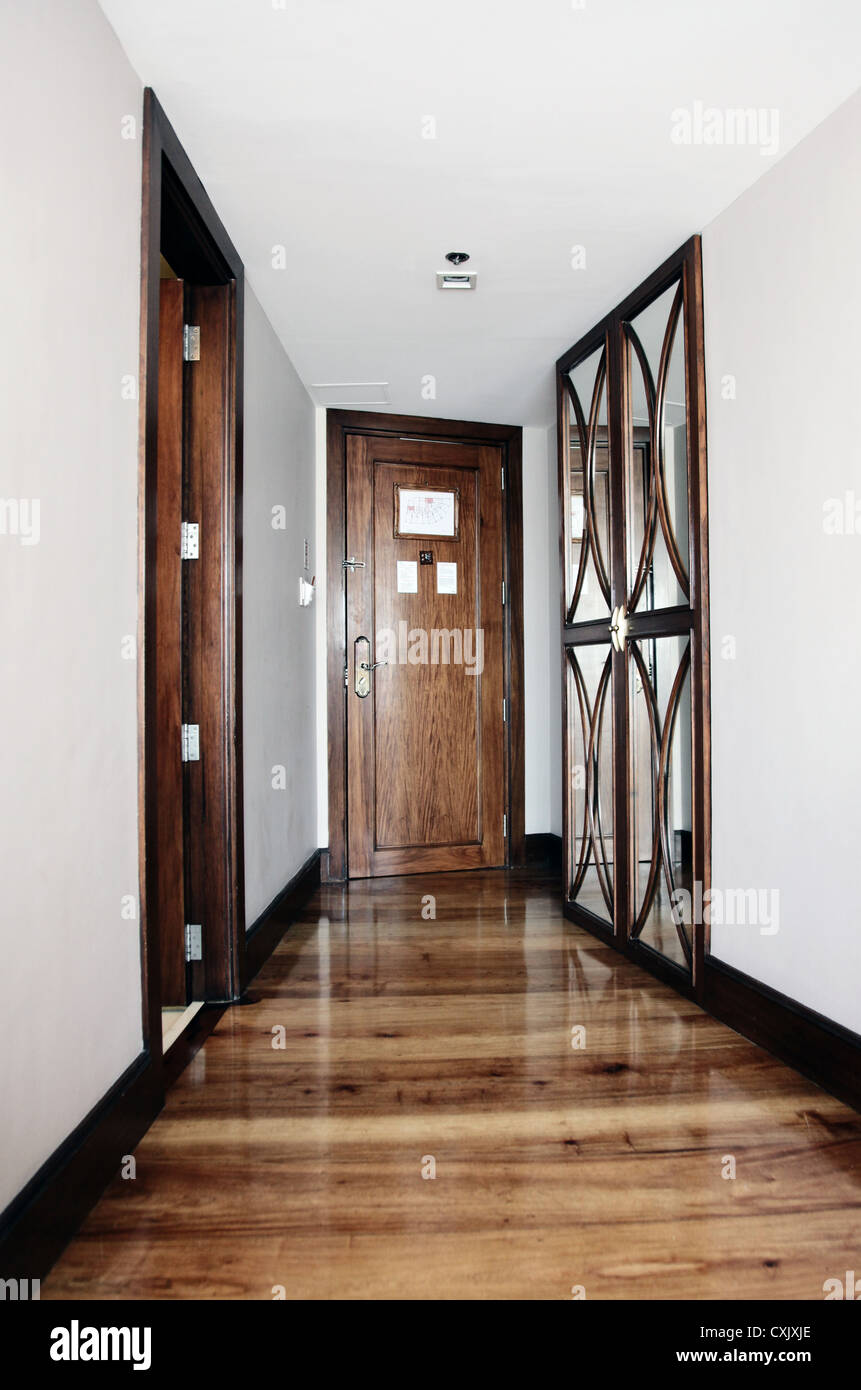 Si tratta di una foto di un corridoio in un appartamento o una camera con una  porta alla fine. Possiamo vedere 3 porte chiuse o aperte. Vi è un pavimento  in legno