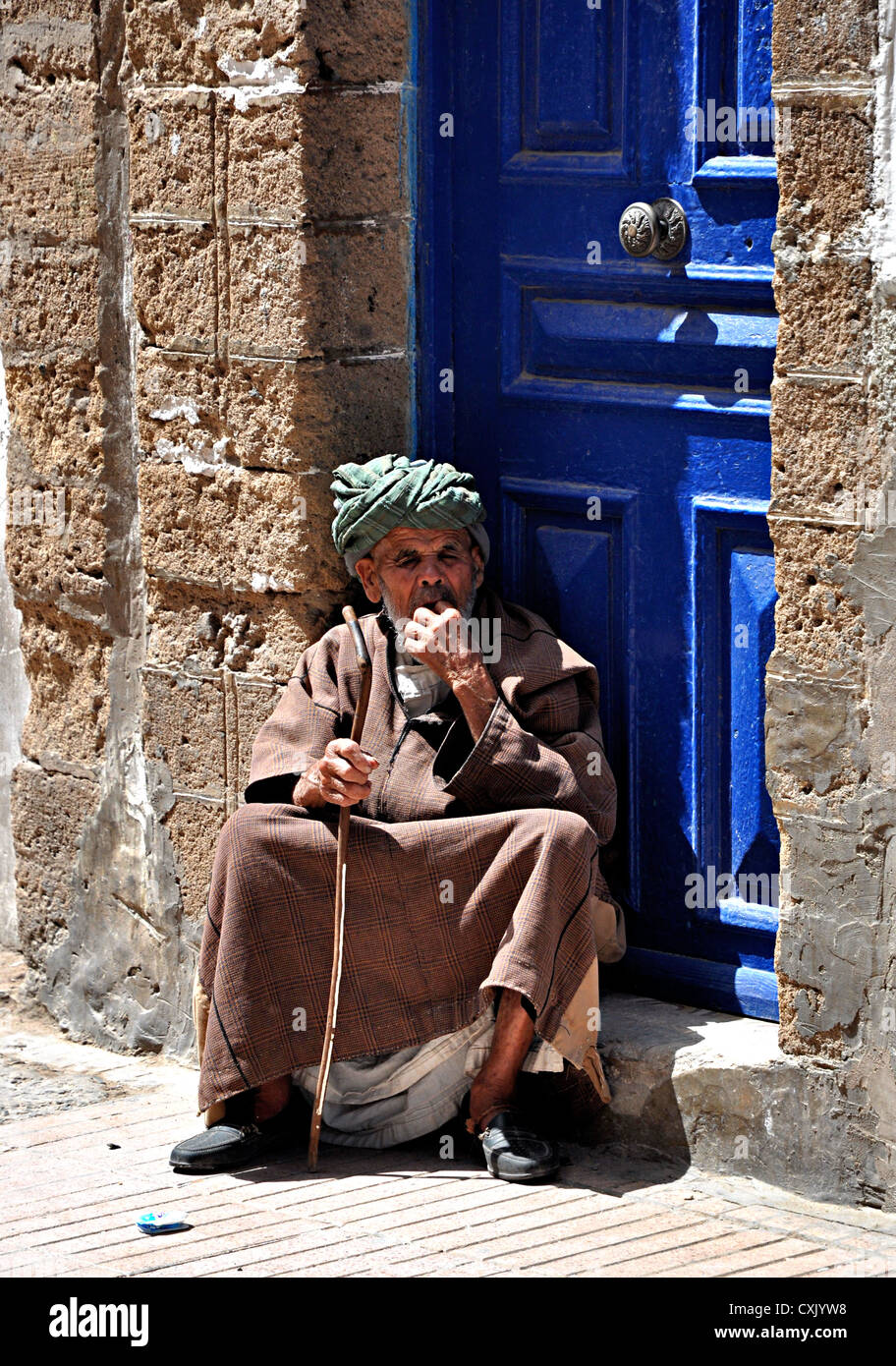 Uomo anziano indossando djellaba e turbante seduti nelle strade della medina di Essaouira, Marocco Foto Stock