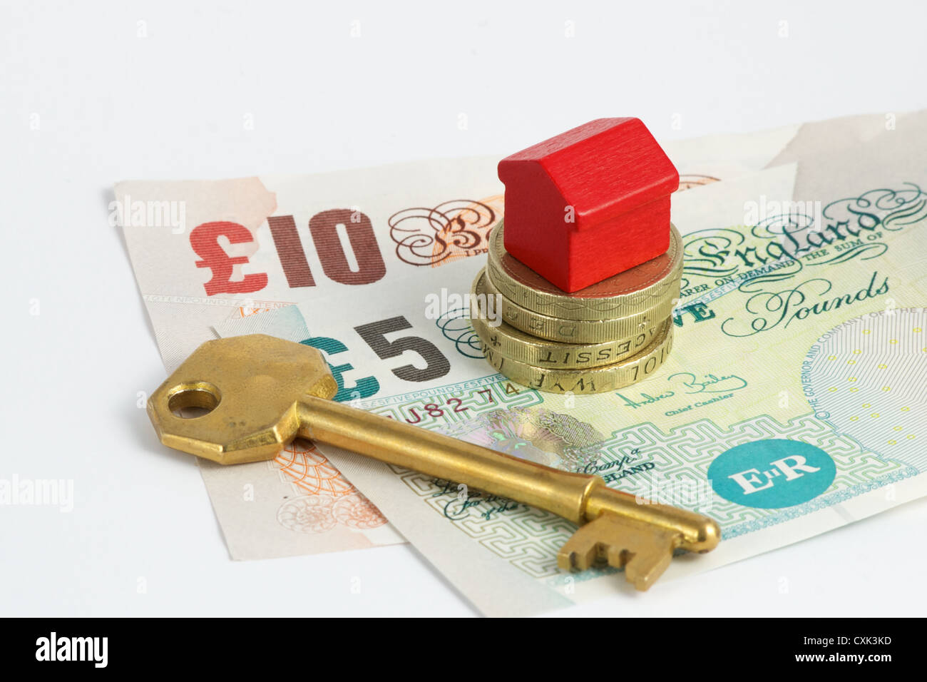 Chiave, British denaro e casa giocattolo insieme su uno sfondo bianco Foto Stock