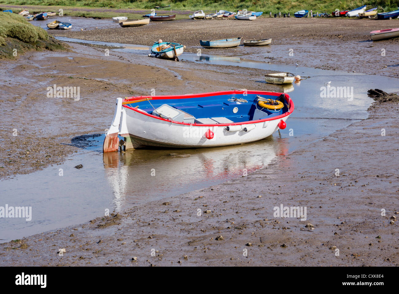 Una colorata barca arenarsi a bassa marea in Morston creek, Morston, Norfolk Foto Stock