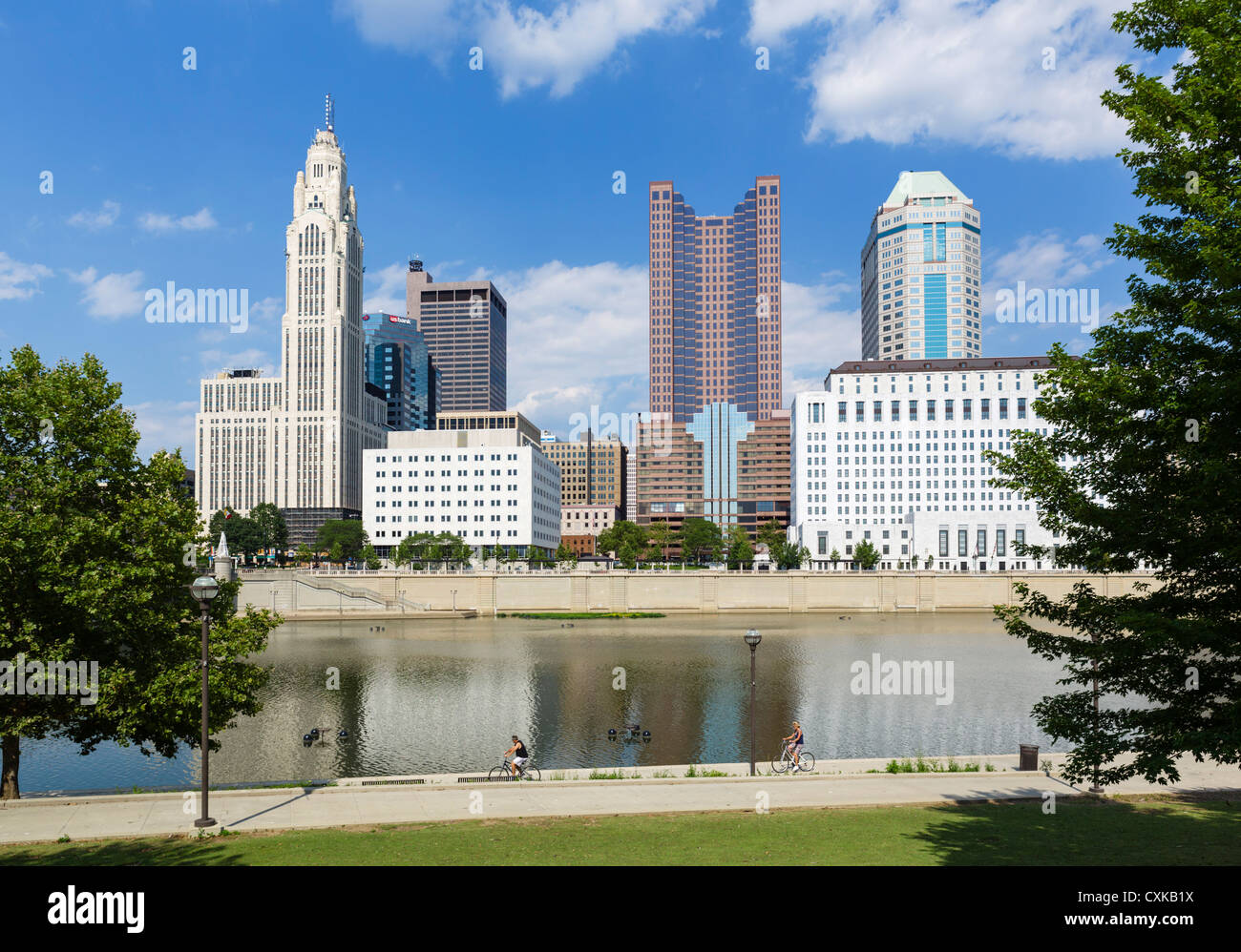 I ciclisti sul sentiero lungo il fiume Scioto con lo skyline della città dietro, Columbus, Ohio, Stati Uniti d'America Foto Stock