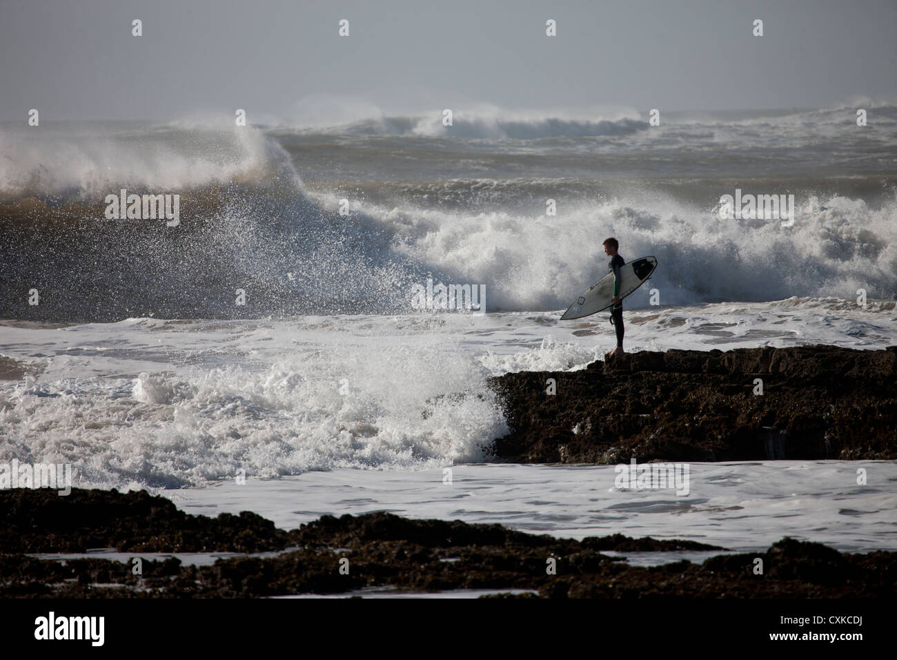 Surfer con tavola da surf guardando le onde dell'Oceano Atlantico, Marocco Foto Stock