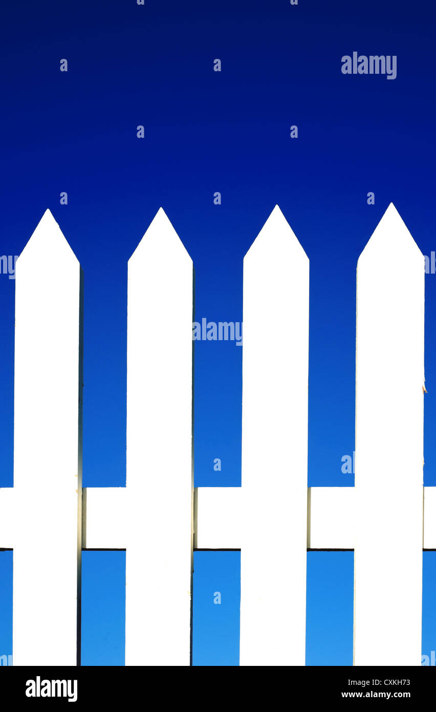 Un white Picket Fence sfondo nella parte anteriore di un luminoso blu cielo con copia spazio. Foto Stock