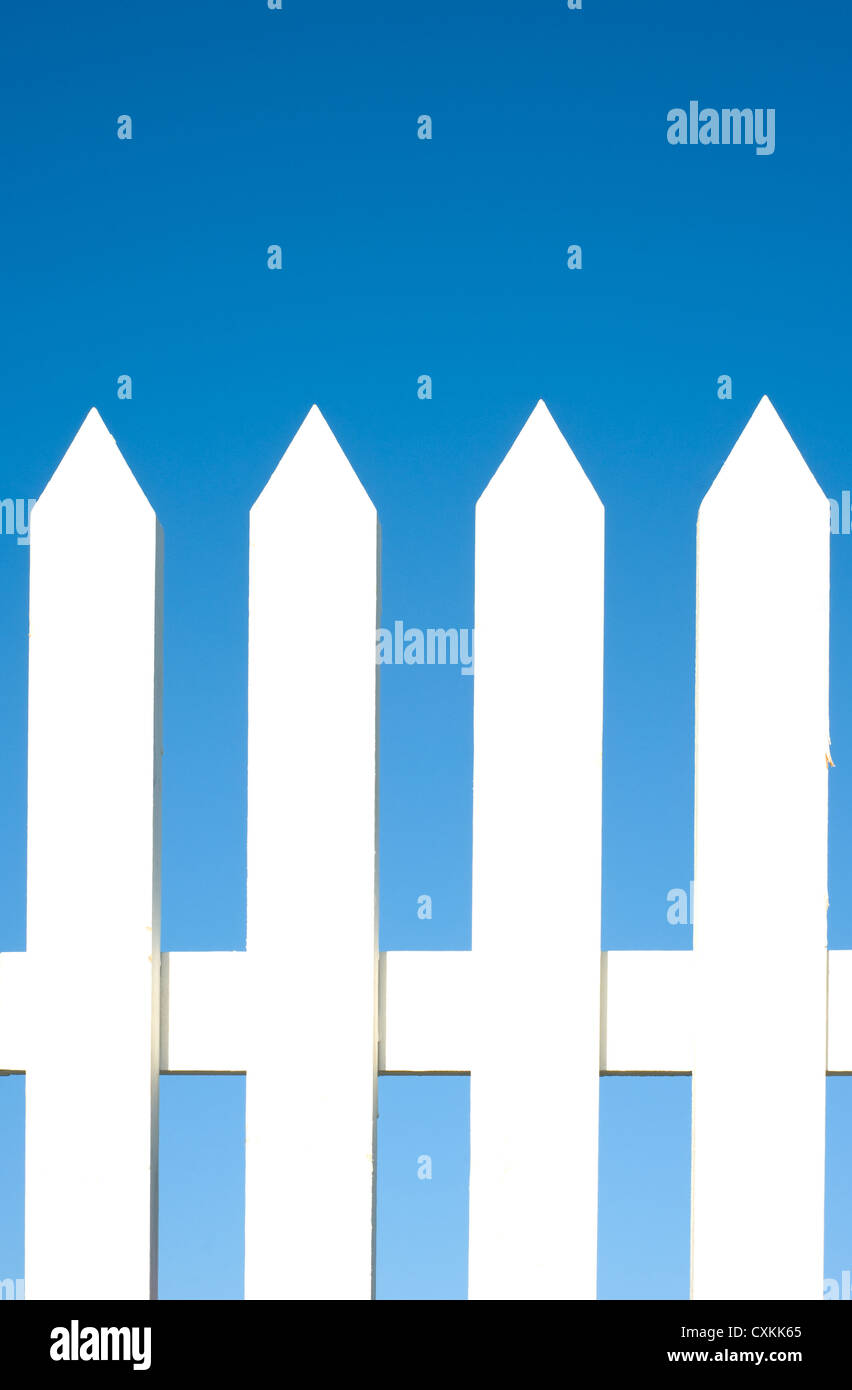 Un white Picket Fence sfondo nella parte anteriore di un luminoso blu cielo con copia spazio. Foto Stock