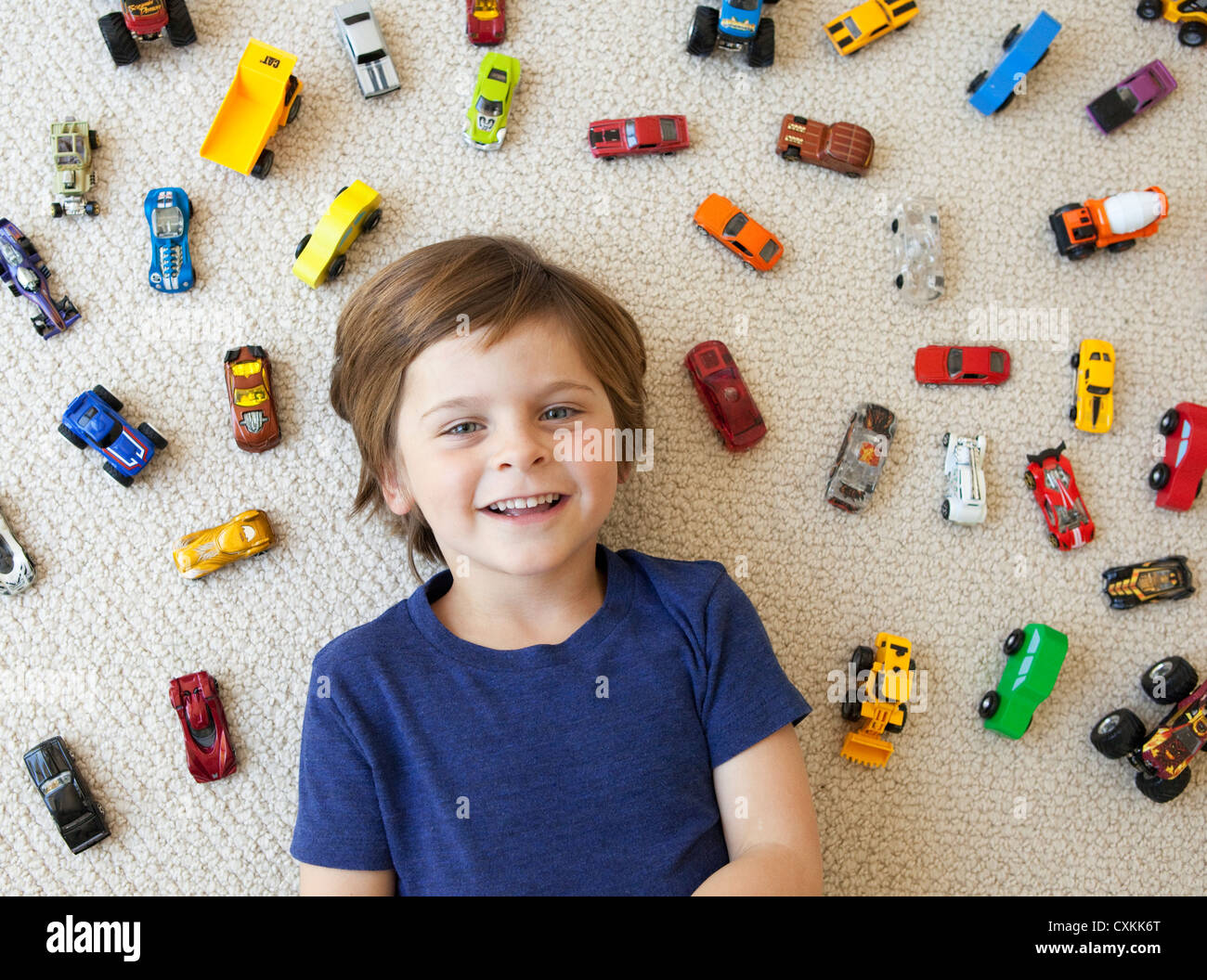 Giovane ragazzo circondato da automobili giocattolo Foto Stock