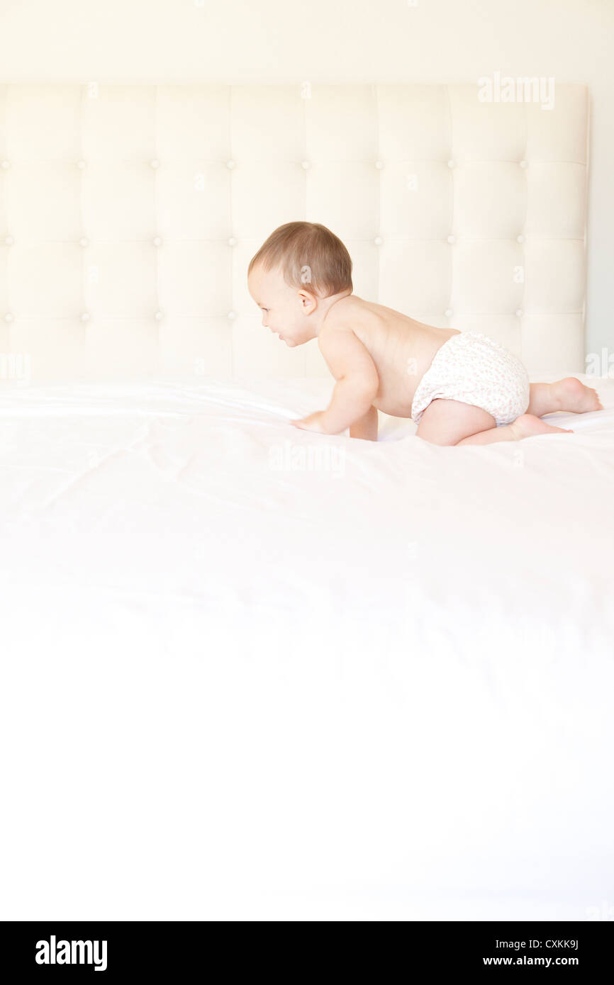 Baby nel pannolino strisciando sul letto Foto Stock