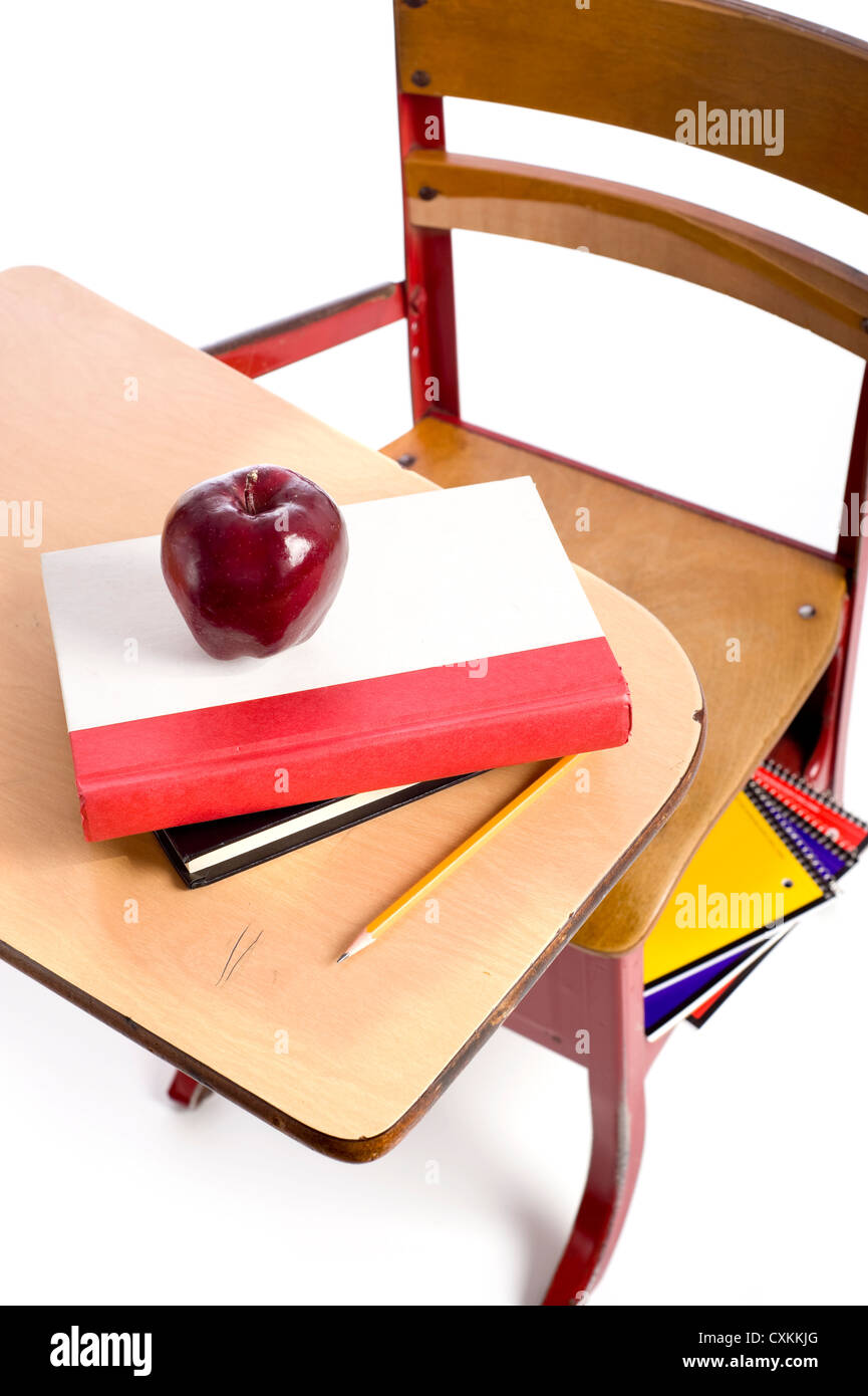 Un vintage banco di scuola con i libri di scuola, una mela rossa e una matita su uno sfondo bianco con spazio di copia Foto Stock