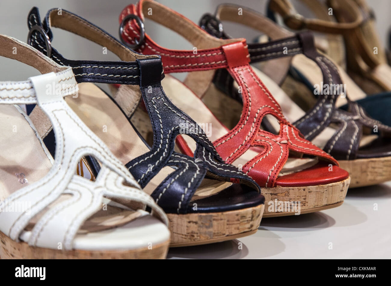 Una fila di colorati in pelle sandali femminile su uno scaffale di un negozio di calzature. Foto Stock