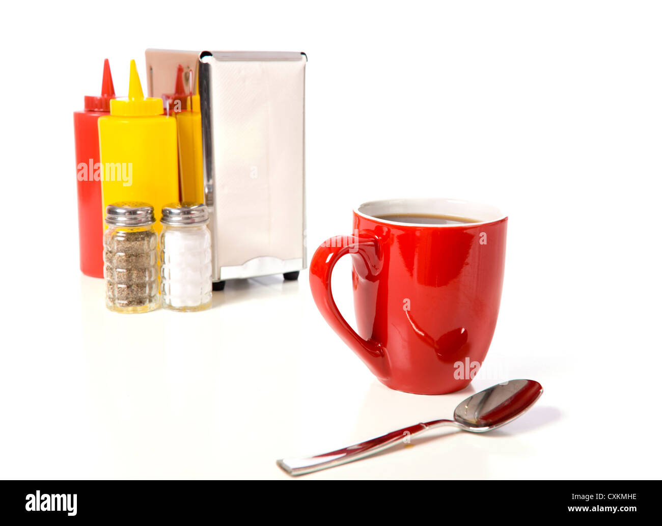 Red tazza da caffè con cucchiaino su una tabella di caffè con ketchup e senape, il sale e il pepe e portatovaglioli Foto Stock