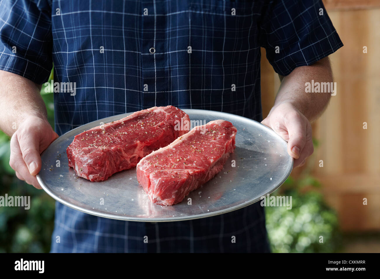 L'uomo tenendo il vassoio con il formato Raw delle bistecche Foto Stock