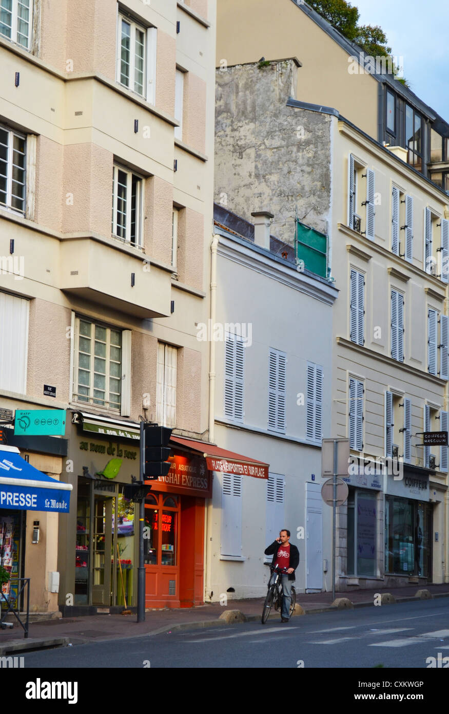 Un ciclista smette di fare una telefonata in una tipica di Parigi scena suburbana. Foto Stock