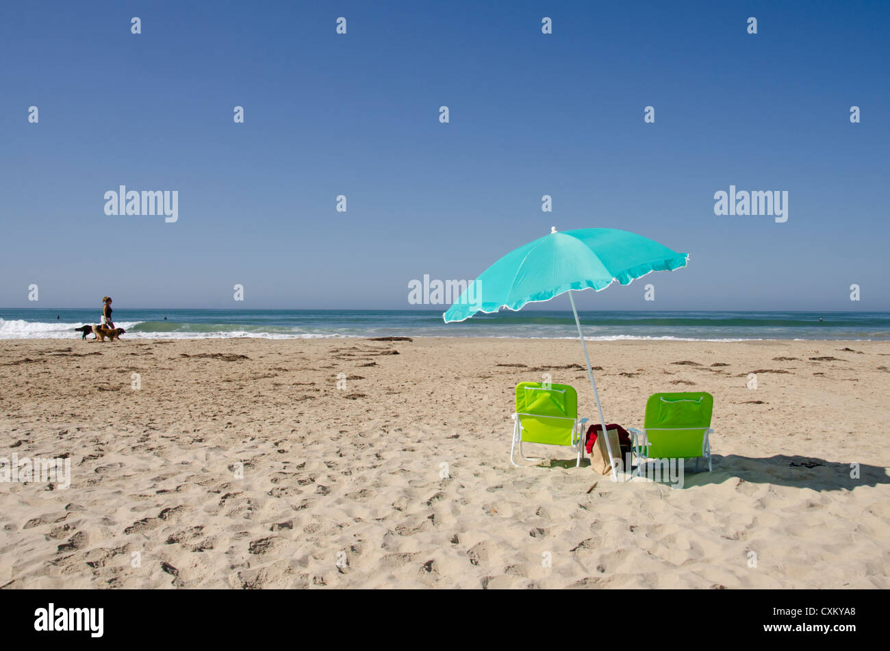California, Pacific Coast, Pismo Beach. Ombrellone e sedie vuote sul Pismo State Beach. Donna pochi cani. Foto Stock