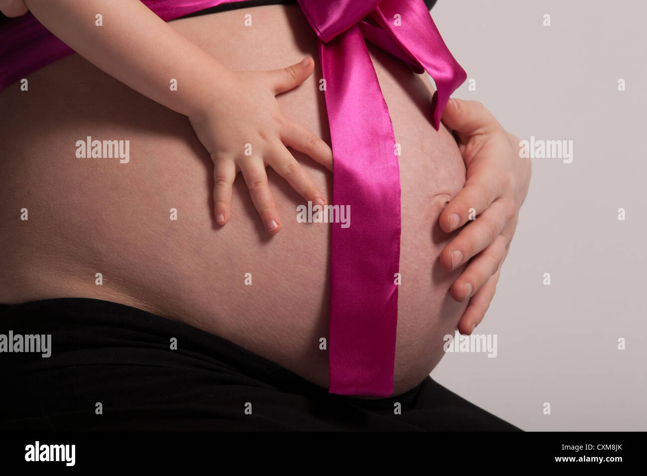 Bambini e madri mano sul ventre in gravidanza Foto Stock