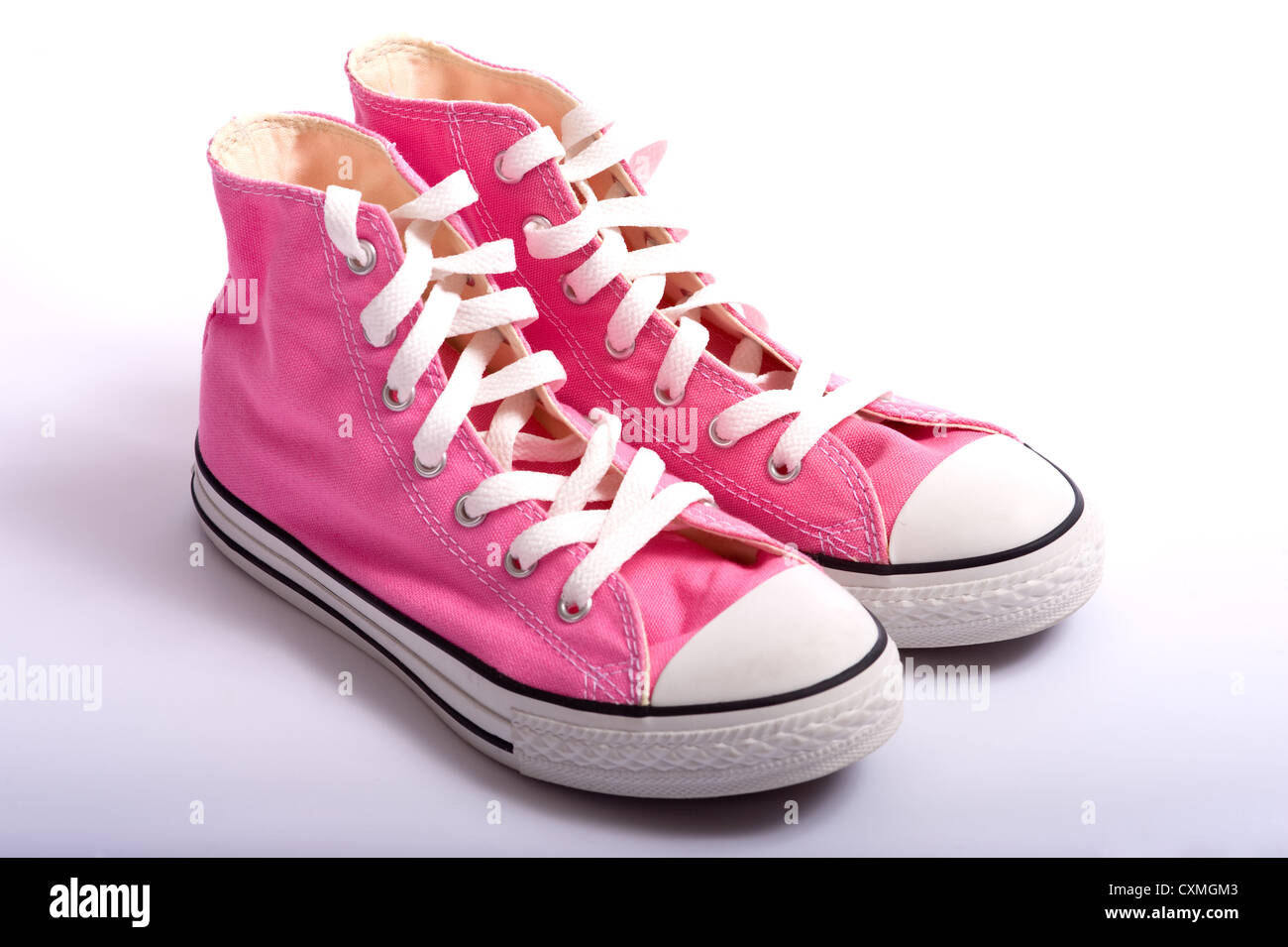 Una coppia di rosa in stile vintage canvas scarpe da basket o sneakers su uno sfondo bianco con spazio di copia Foto Stock
