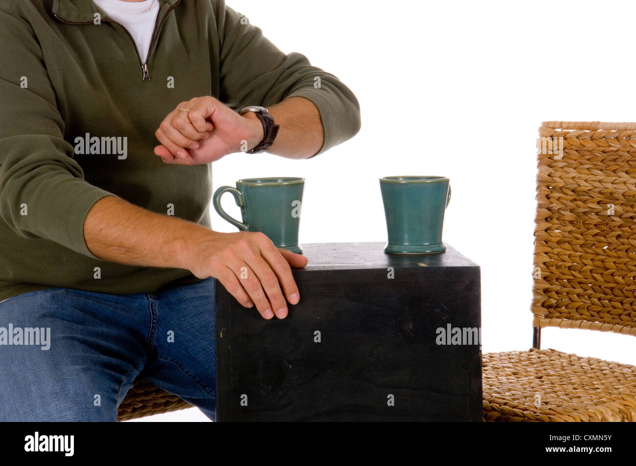 Casual Male controllare il suo orologio presso la caffetteria contro uno sfondo bianco, con una sede vuota, avrebbe potuto essere si alzò in piedi Foto Stock