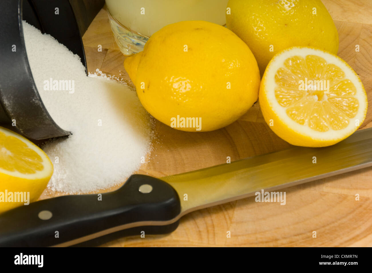 I limoni, zucchero e il coltello sul tagliere. ingredienti per la limonata Foto Stock
