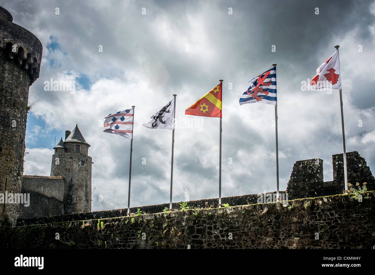 Bandiere svolazzanti in un vento forte in cima le pareti di pietra del borgo medievale fortificato di Chateau de Fougeres in Bretagna, Francia. Foto Stock