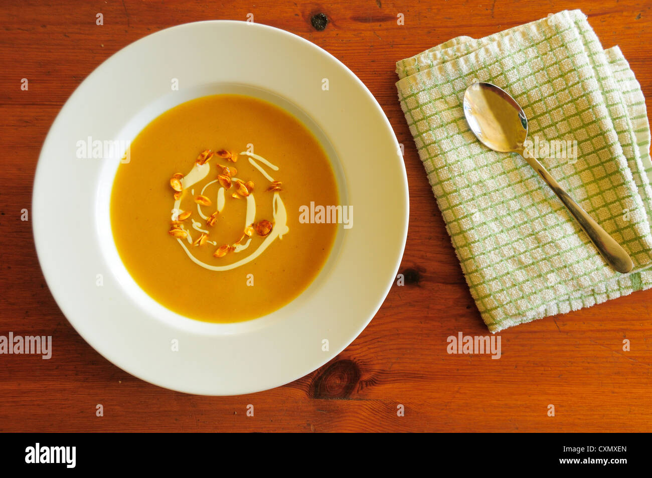 Arrosto di zucca minestra sulla tavola di legno in bianco pulito ciotola, guarnita con creme fraiche e semi caramellati Foto Stock
