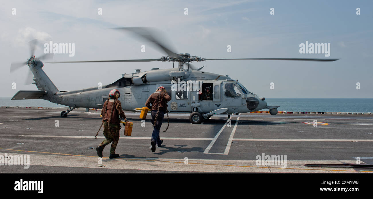 Aviation Structural Mechanics dell'Helicopter Sea Combat Squadron 8, Holly Degroot e Joshua Best, si assicureranno un elicottero MH-60S Knighthawk a bordo della USS John C. Stennis nello stretto di Malacca, preparando l'aereo per la partenza. Foto Stock