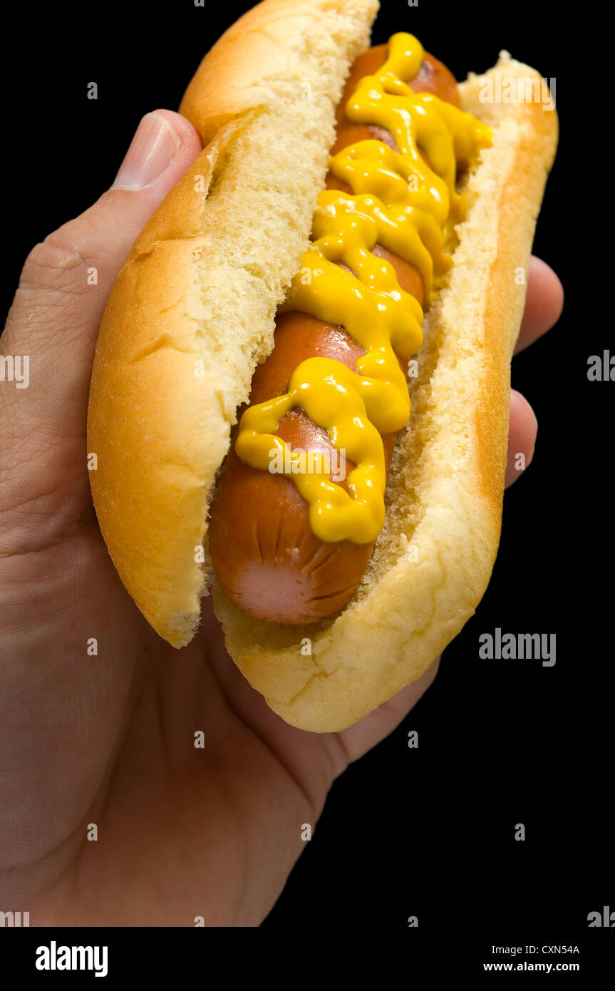 Hot Dog con senape in mano su sfondo nero Foto Stock
