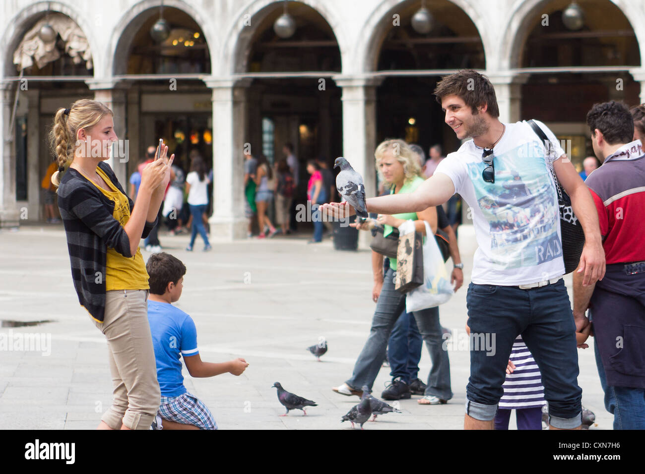 Turista giovane per scattare delle foto e la alimentazione di piccioni in Piazza San Marco Venezia Italia Foto Stock