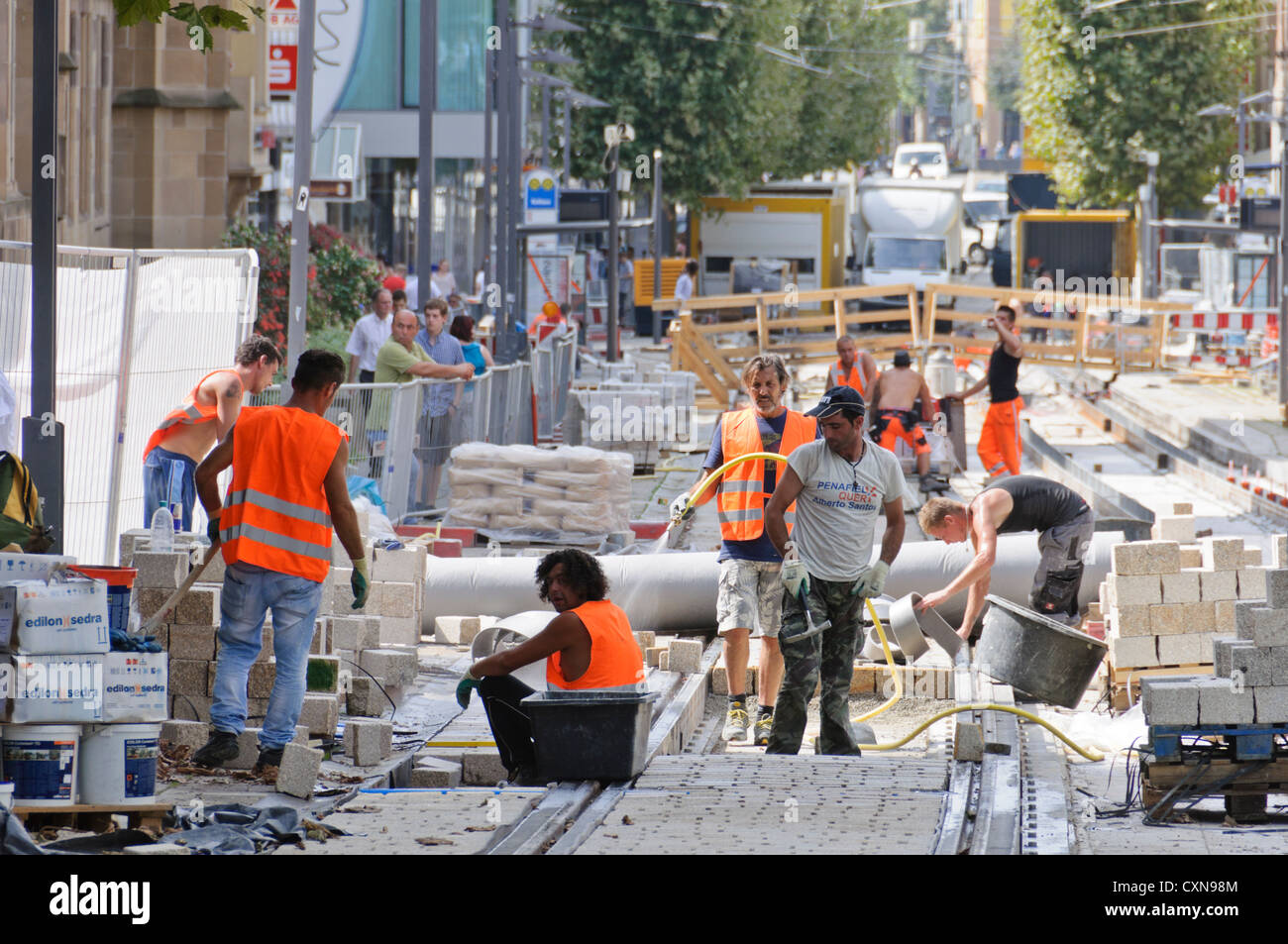 Binario ferroviario sito in costruzione con multirazziale operai edili nel segnale di colore abito da lavoro, Kaiserstrasse Heilbronn Foto Stock