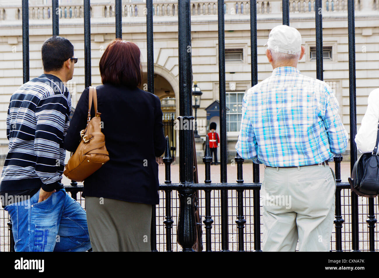 I turisti alla ricerca attraverso le ringhiere fuori Buckingham Palace. Foto Stock