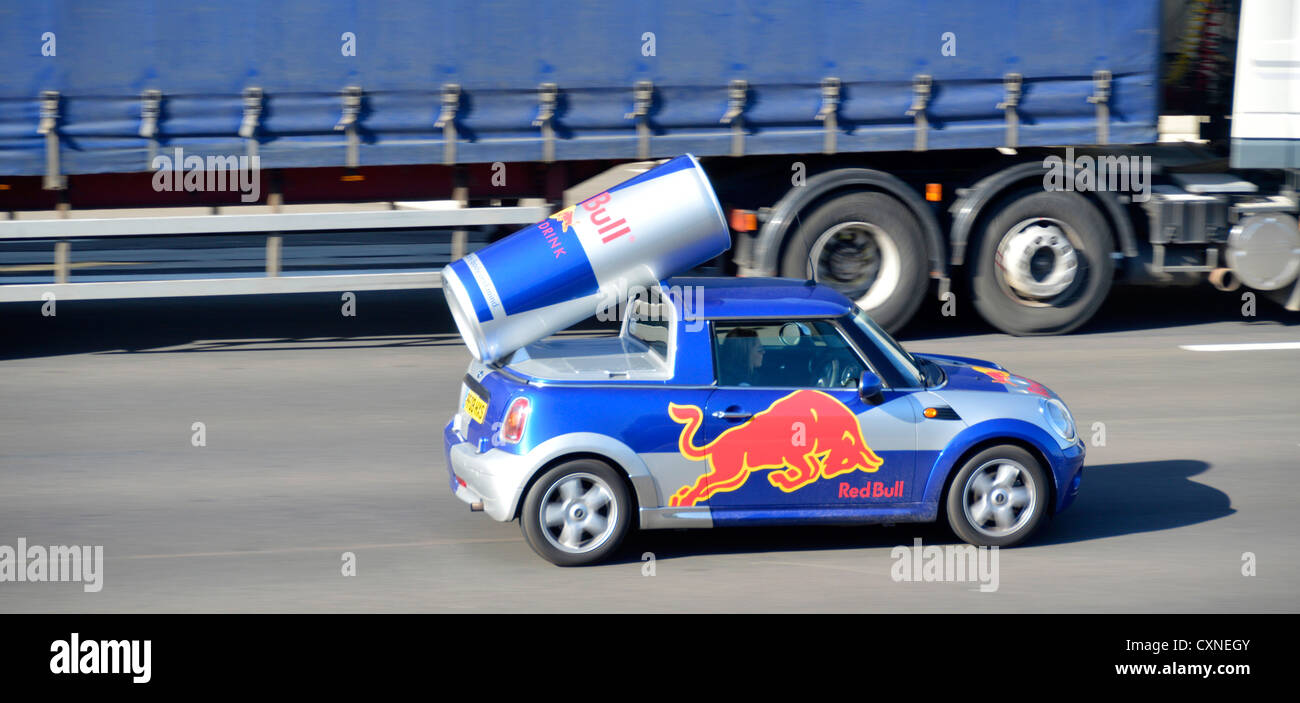 Pubblicità personalizzata Red Bull marchio energia bevanda incorporando grande lattina & logo in mini auto carrozzeria guida su autostrada M25 strada Essex Inghilterra UK Foto Stock
