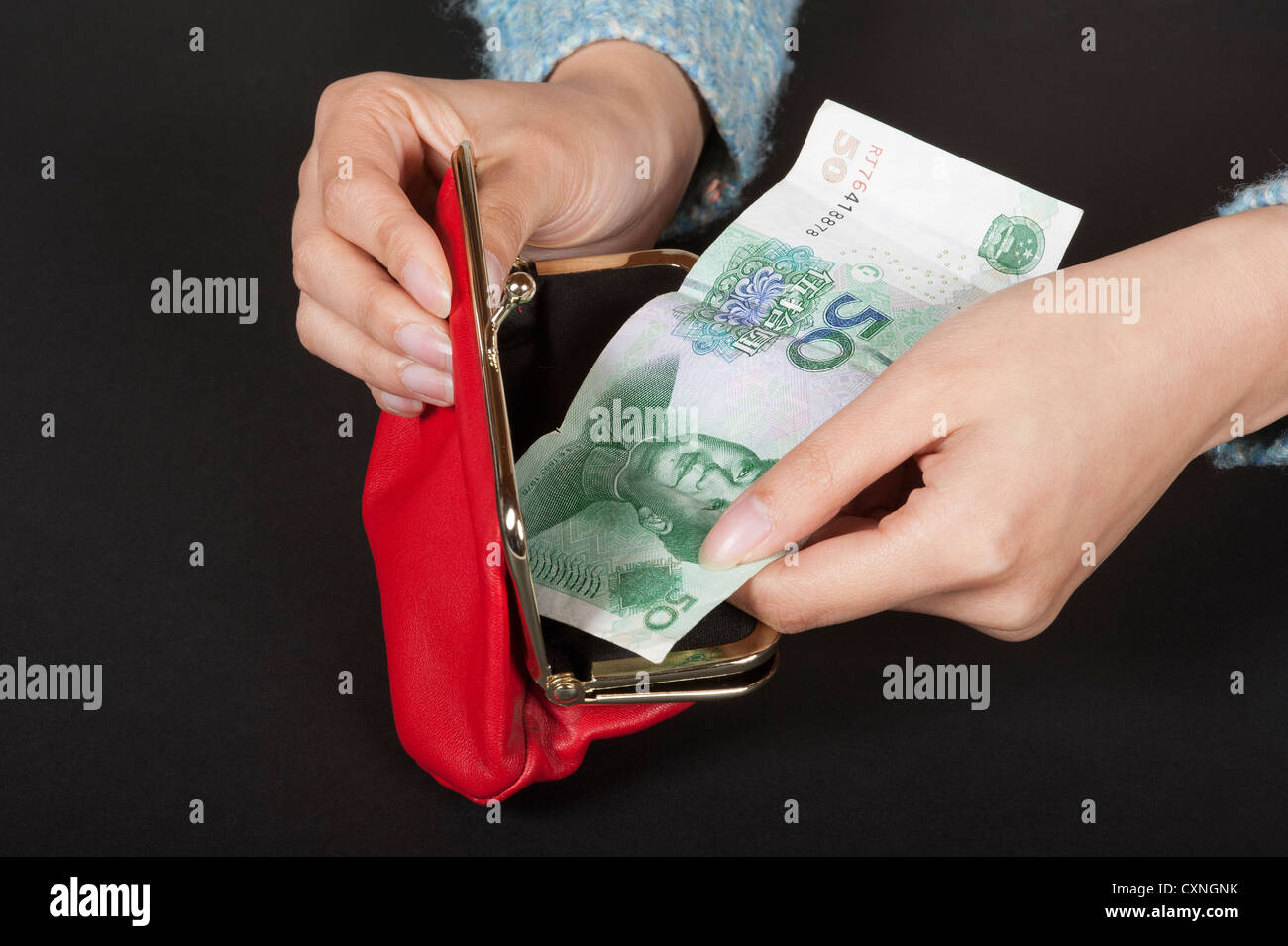 Giovane donna la mano prendendo un cinese 50 Yuan banconota da un portamonete rosso Foto Stock