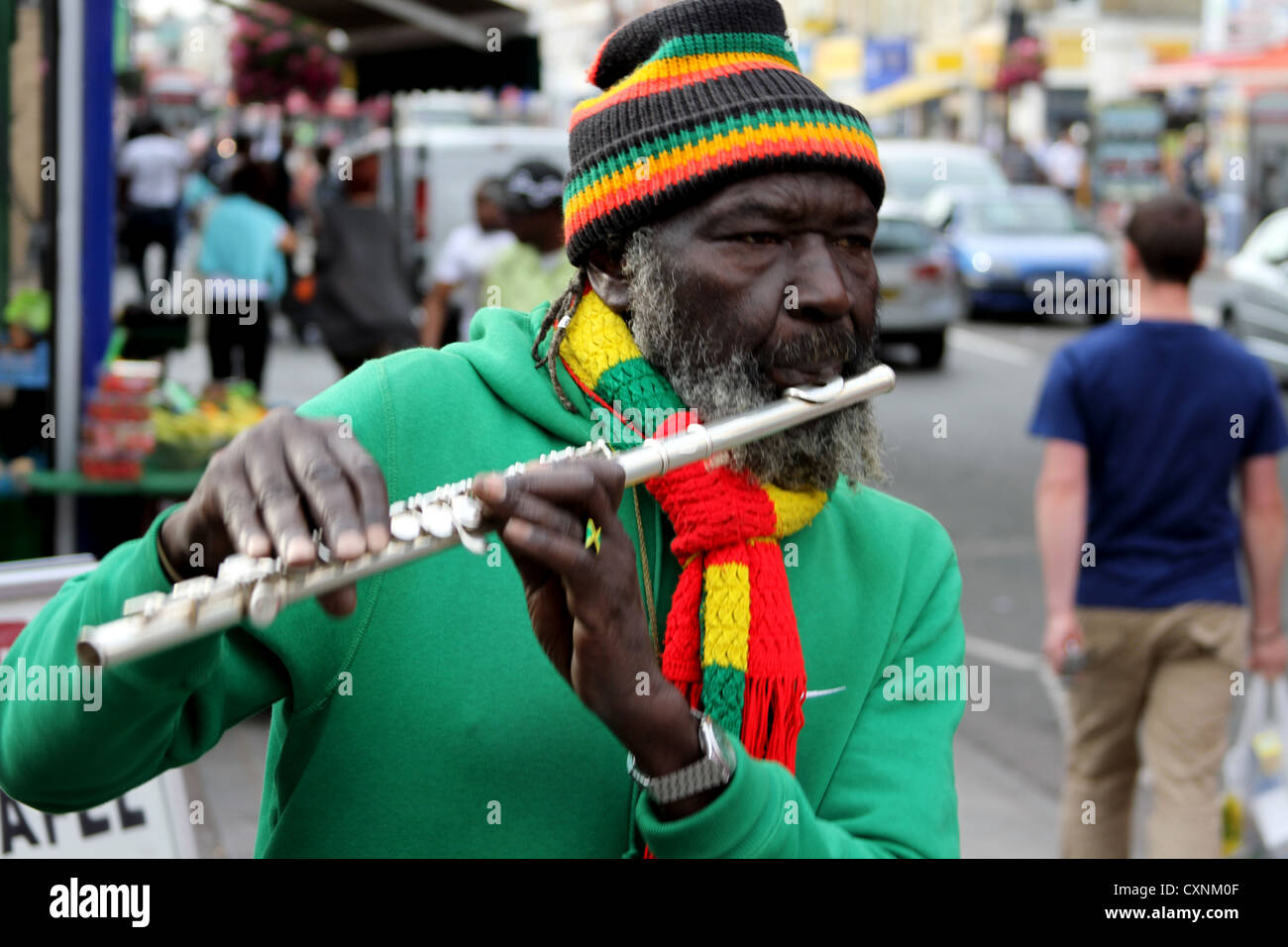 Giocatore di flauto africano in strada uomo caucasico a piedi dietro Foto Stock