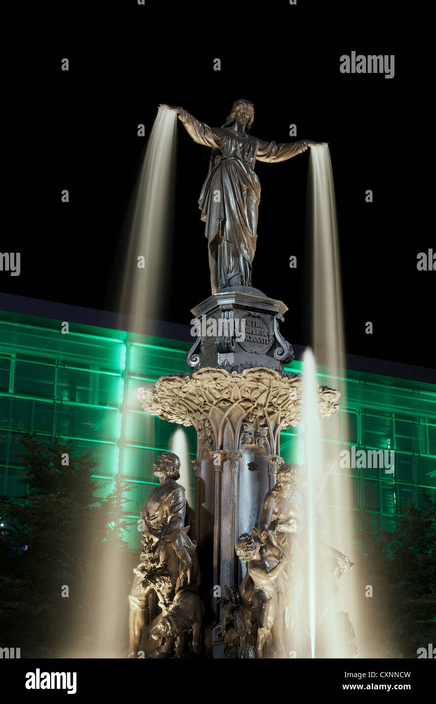 Tyler Davidson genio della fontana in Piazza Fontana, Cincinnati a notte con green building illuminato Foto Stock