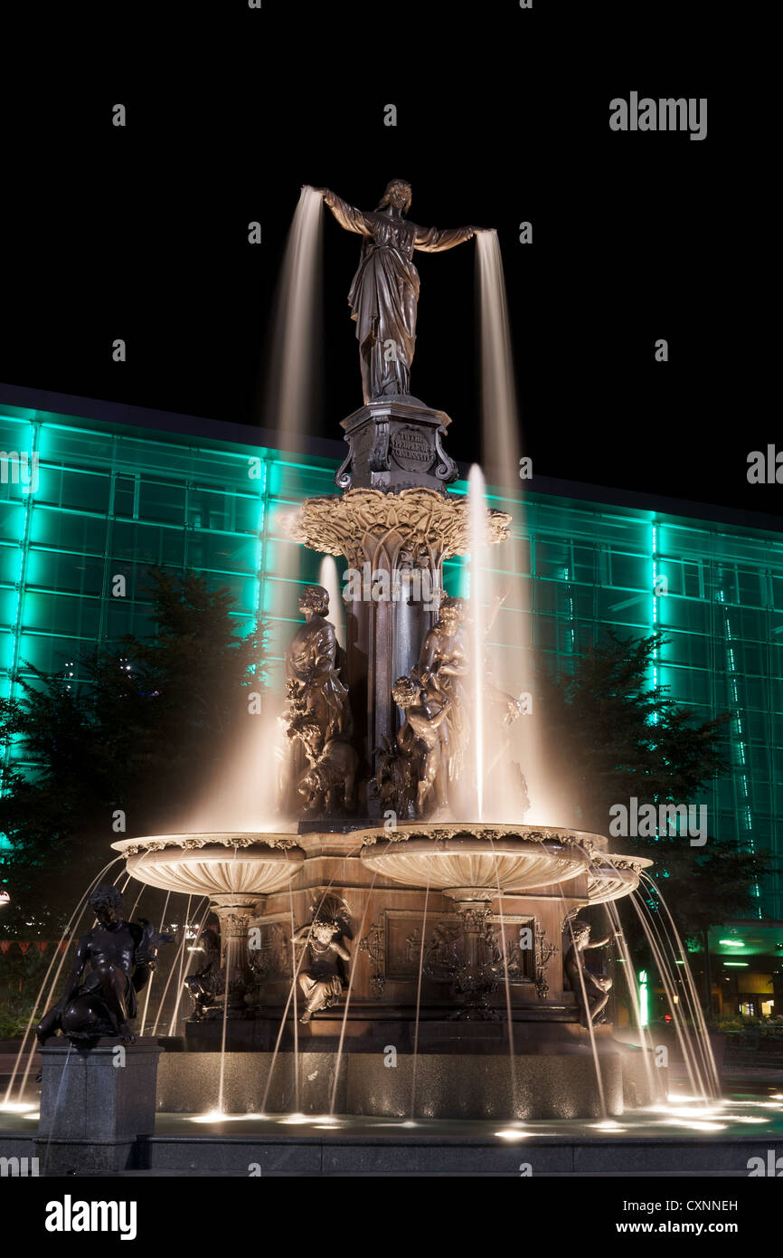 Tyler Davidson genio della fontana in Piazza Fontana, Cincinnati a notte con green building illuminato Foto Stock