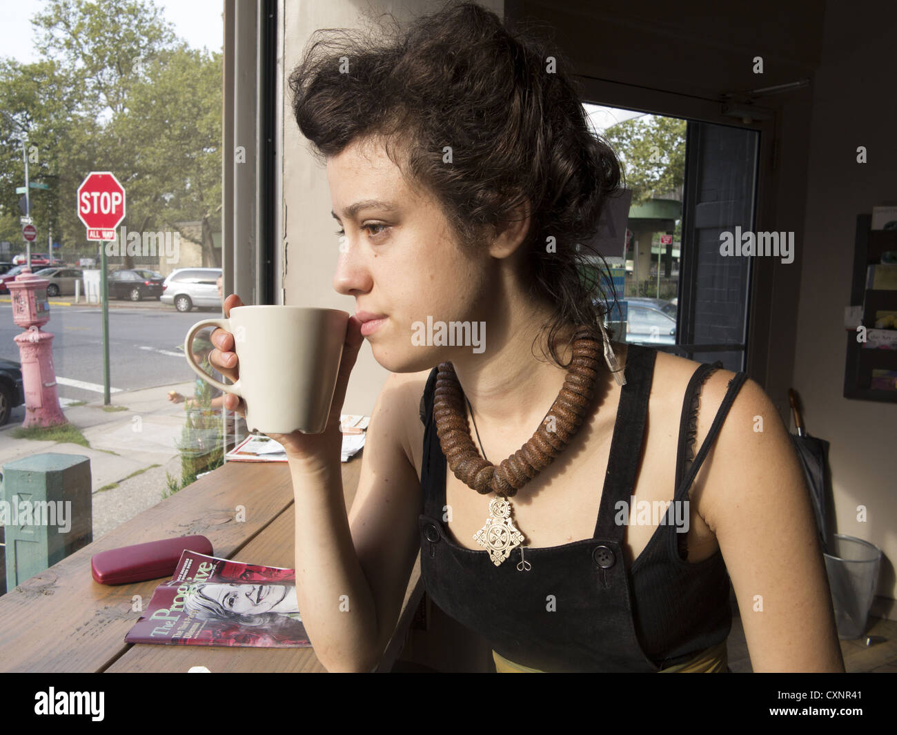 Giovane donna meditando qualcosa su una tazza di caffè in uno dei bar di Brooklyn, New York City. Foto Stock