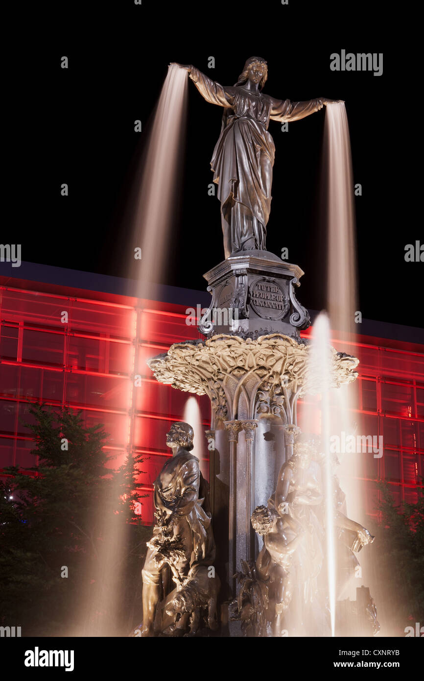 Tyler Davidson genio della fontana in Piazza Fontana, Cincinnati a notte con rosso edificio illuminato Foto Stock