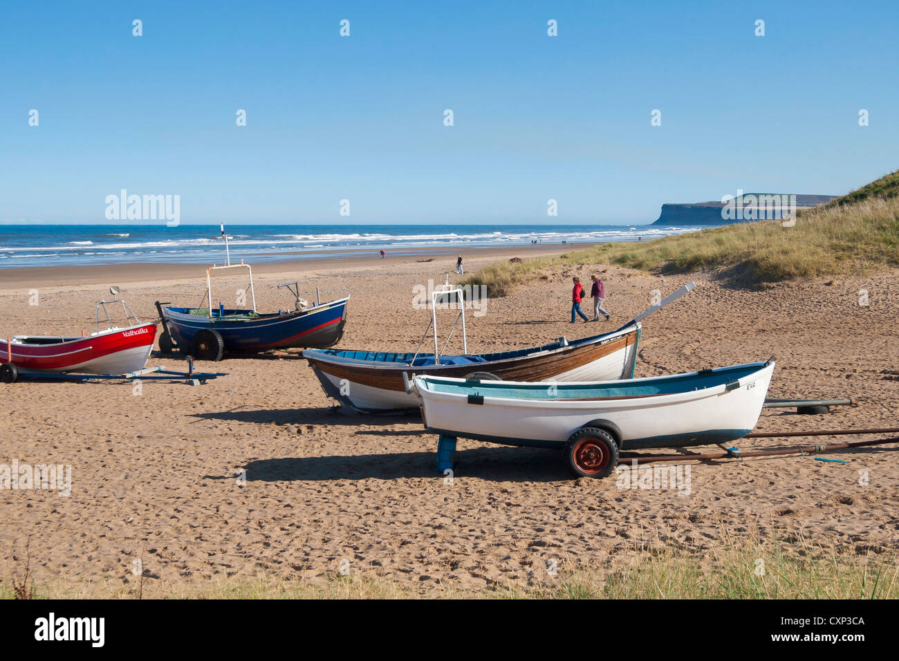 Su un soleggiato autunno domenica pomeriggio due donne a piedi dalle barche di pescatori sulla spiaggia di Marske Foto Stock