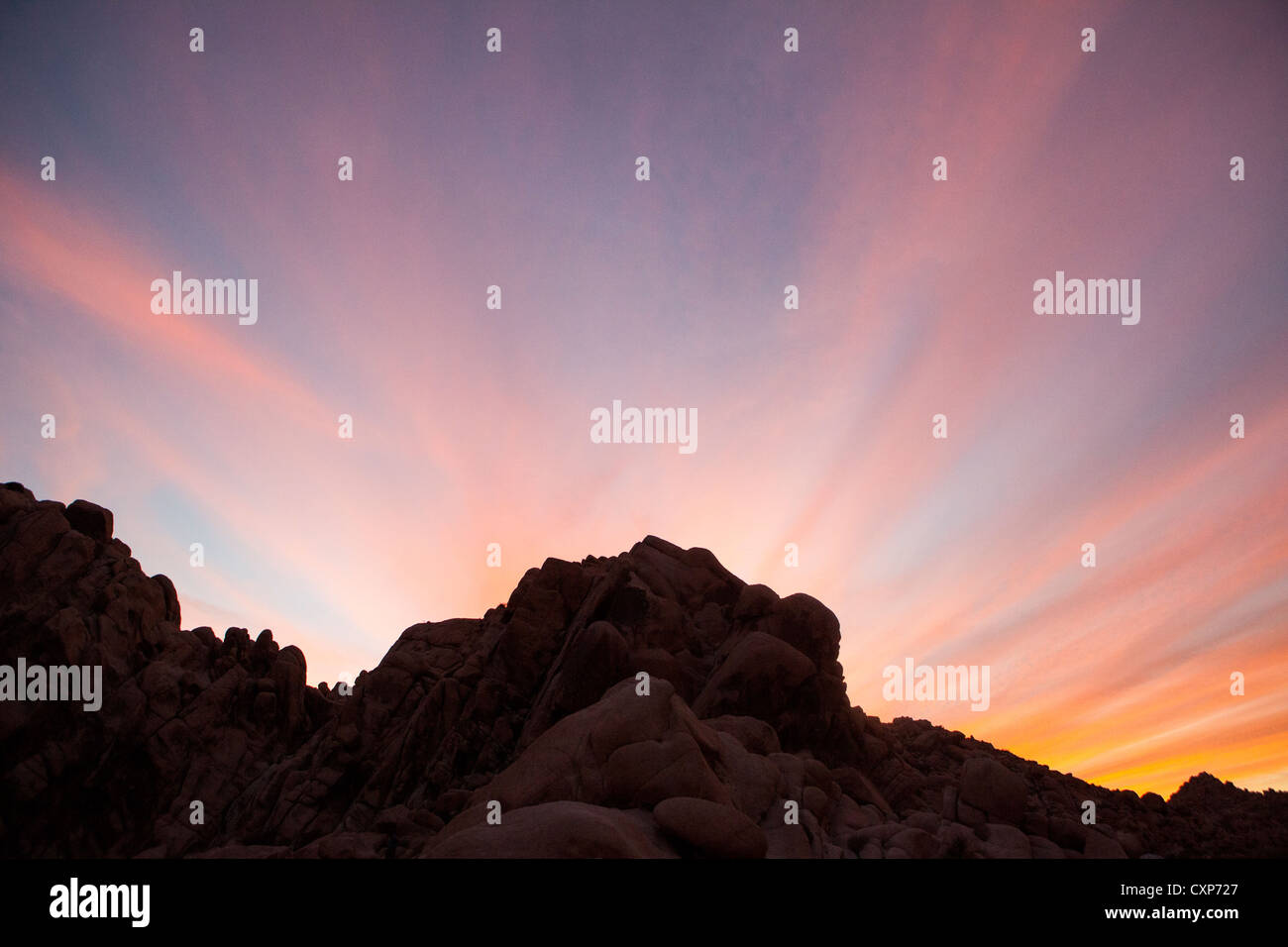 Drammatico tramonto nel deserto con silhouette di rocce e montagne. Foto Stock