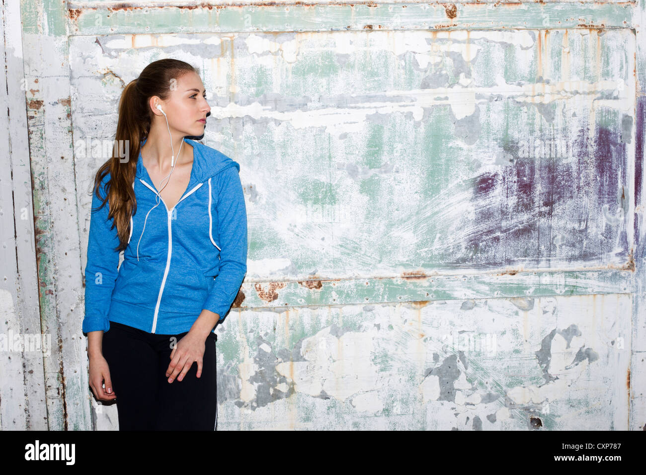 Donna che indossa abiti sportivi in piedi contro un muro in una tuta blu top Foto Stock