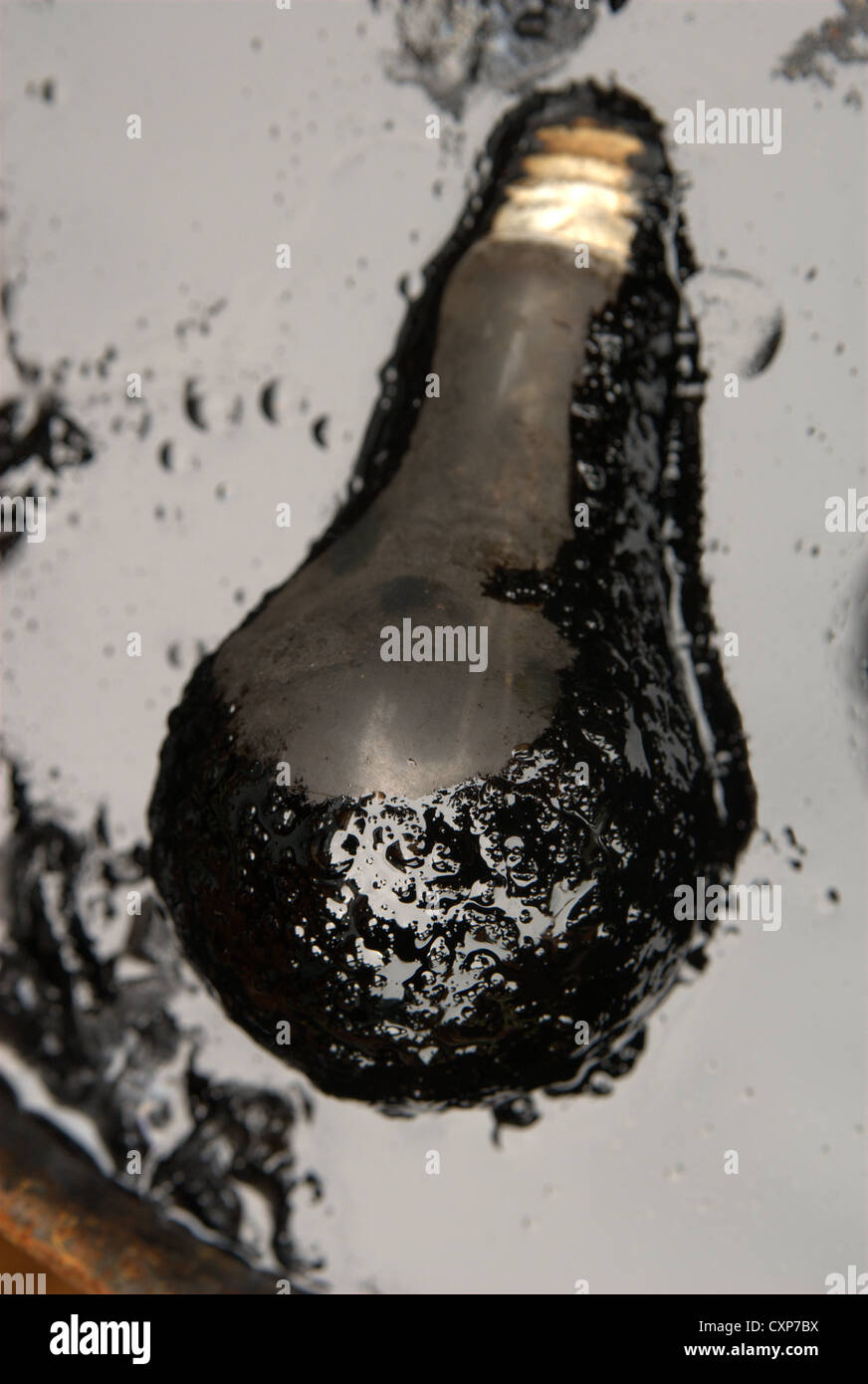 Lampadina luce galleggiante in una pozza di olio Foto Stock