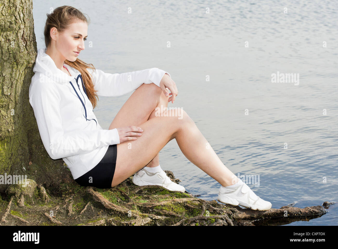 Donna pensando all'aperto da un lago Foto Stock