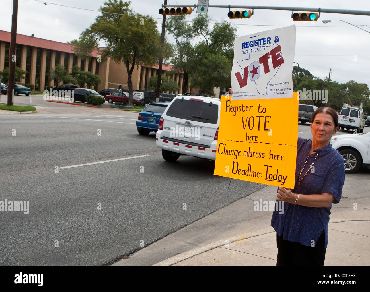 La donna bianca contiene fino segno incoraggiante di driver e passanti in Austin, TX, registrarsi per votare prima di una prossima elezione. Foto Stock