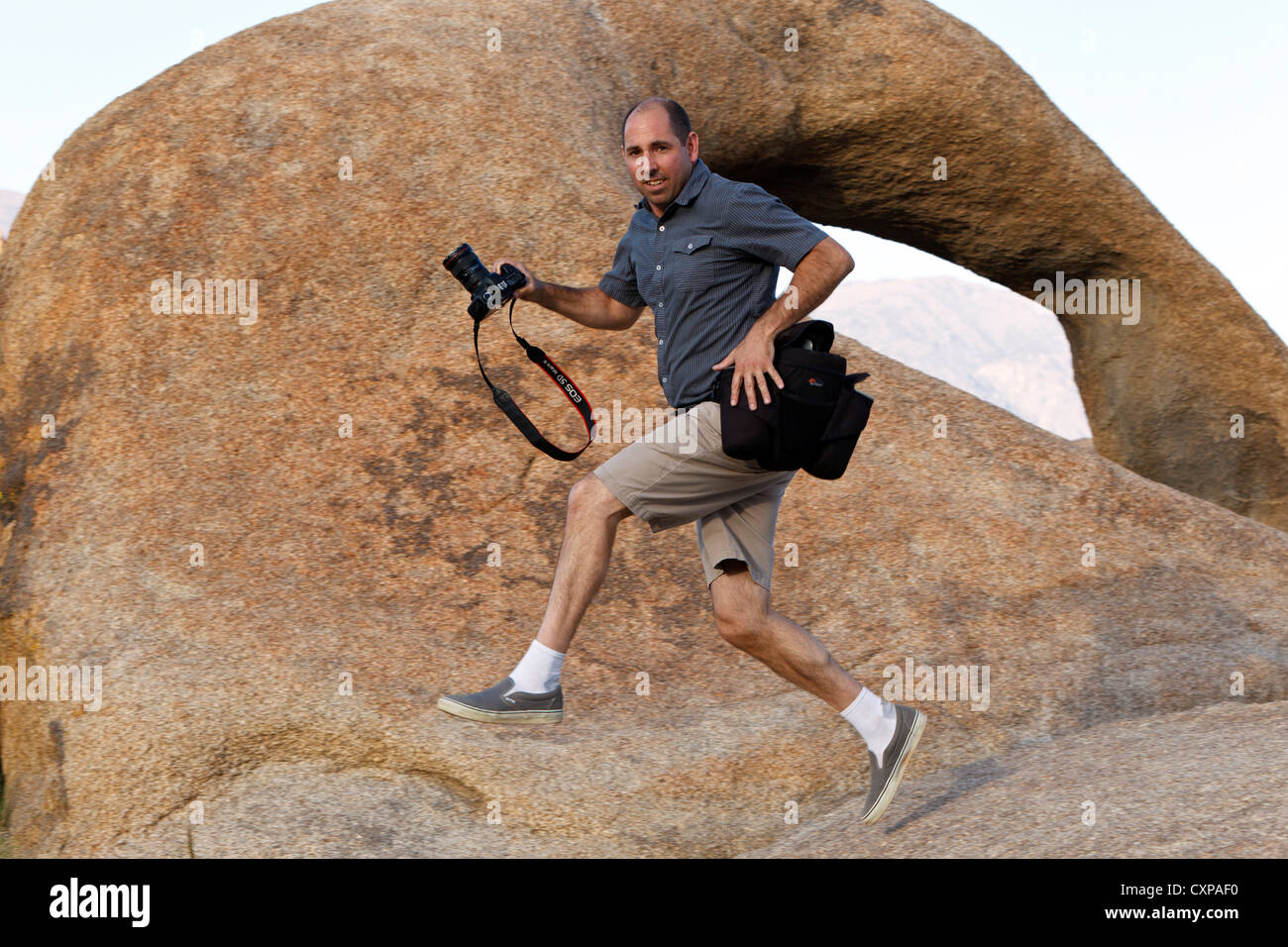 Fotografo jumping passato l'Alabama Hills Arch, Lone Pine, California, Stati Uniti d'America Foto Stock