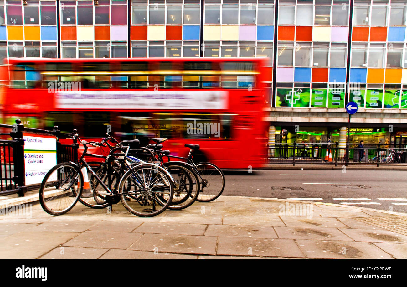 Il red Bus londinese passando attraverso Notting Hill con le biciclette sul parcheggiato sulla stazione di tubo Foto Stock