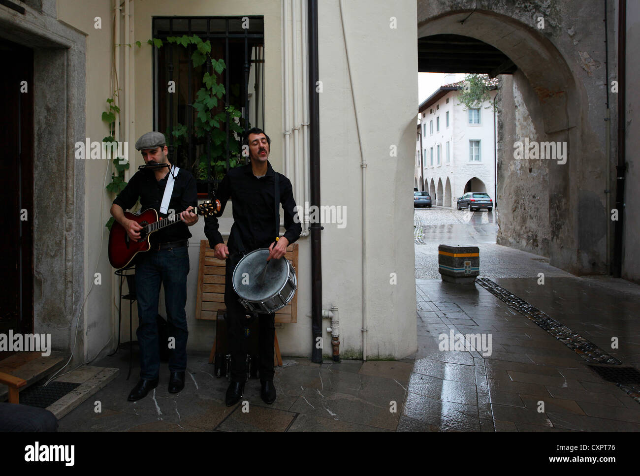 Due musicisti di strada suonando musica folk al di fuori di un wine bar nel centro storico di Spilimbergo, Friuli Venezia Giulia, Italia settentrionale Foto Stock