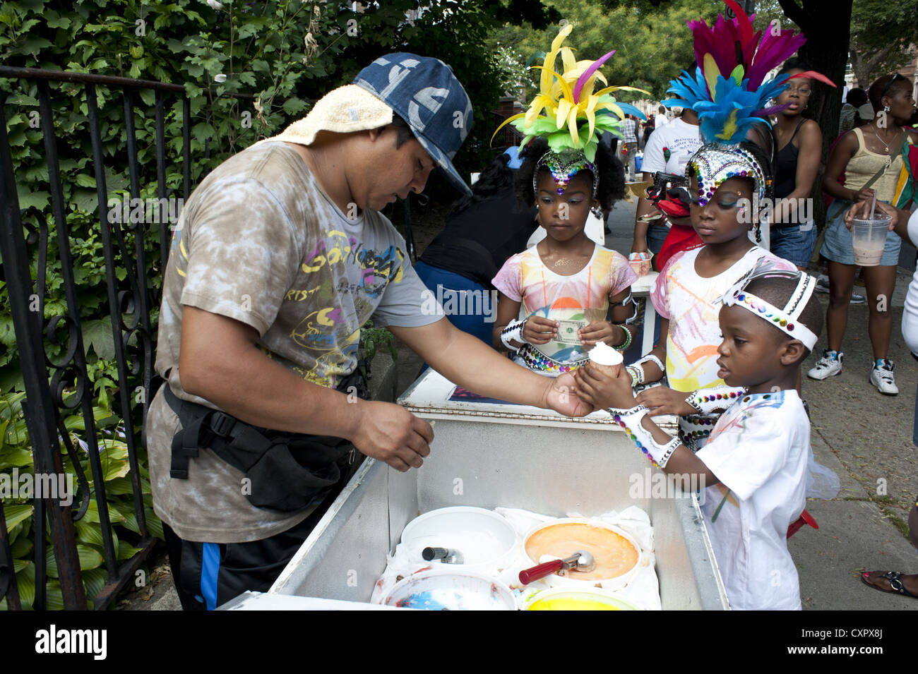USA: Brooklyn, New York. I bambini in costume acquistare ices durante dei Caraibi Kiddies parata del giorno, Crown Heights, 2012. Foto Stock
