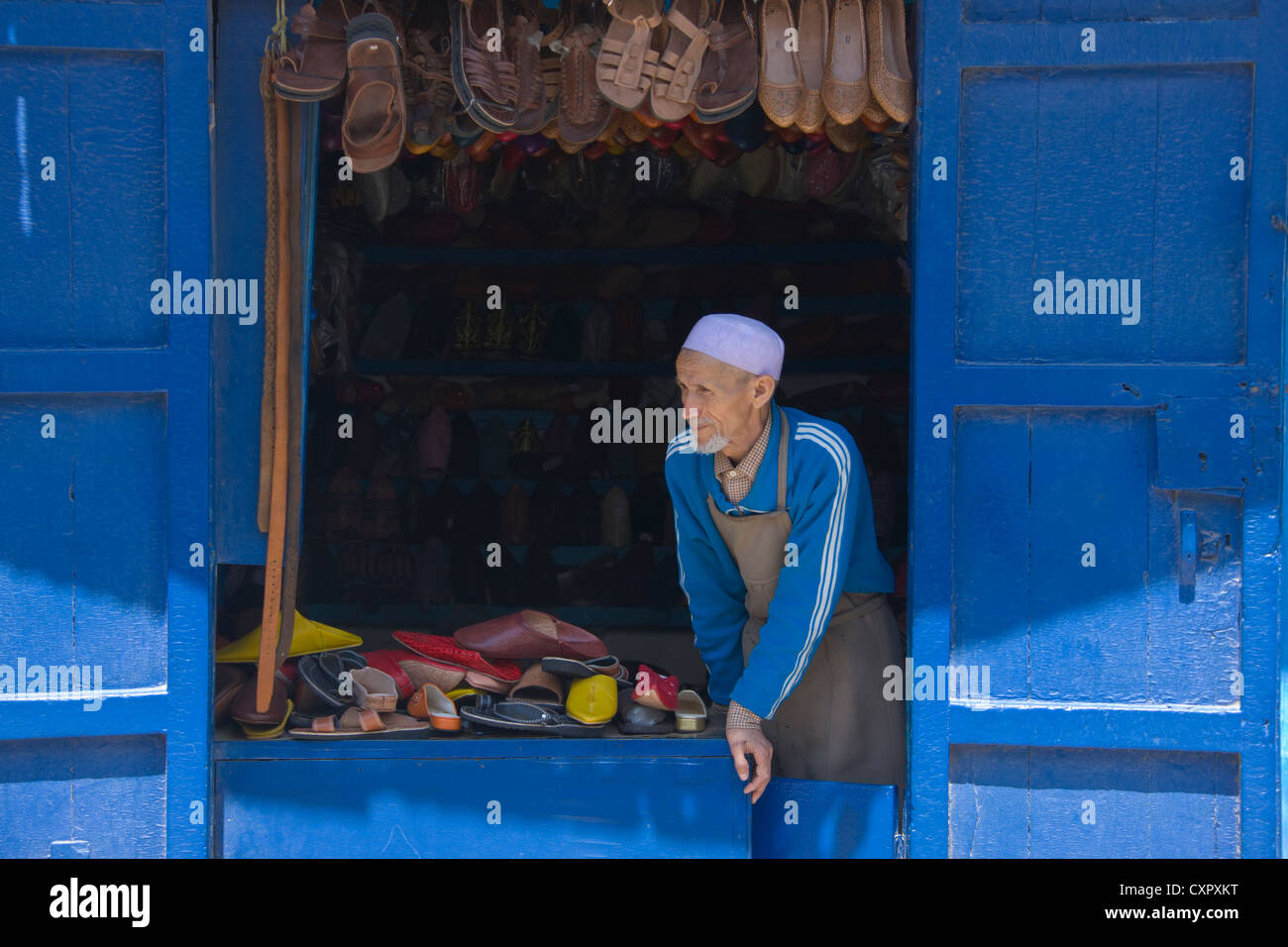 Il vecchio uomo la vendita di scarpe in casa blu nella vecchia medina, Rabat, Marocco Foto Stock